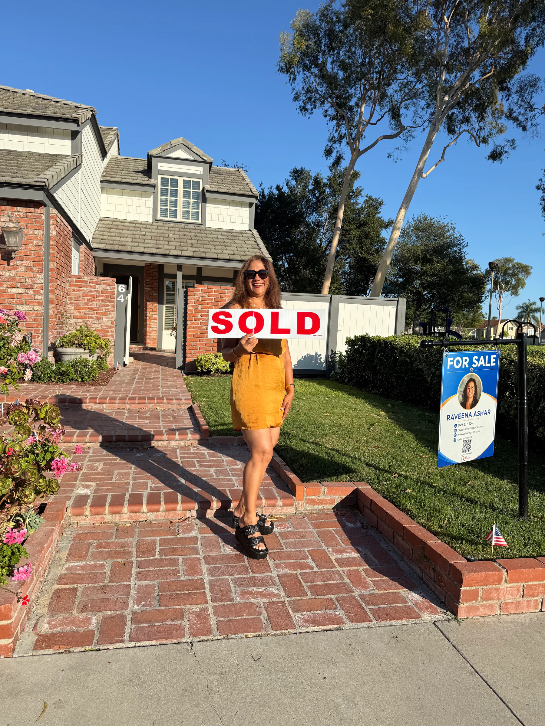 Raveena Ashar holding the sold sign outside 64 Bennington
